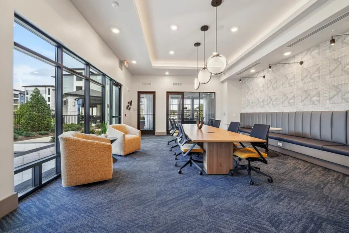 Modern meeting space with chic seating, large windows offering natural light, and stylish pendant lighting.