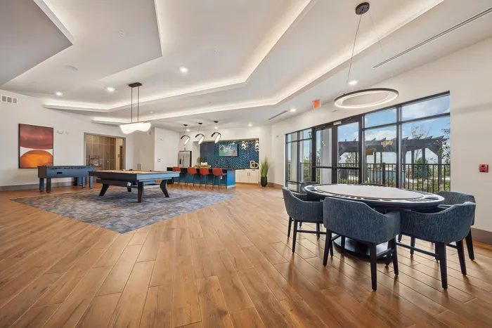Elegant lounge area with modern lighting, billiard table, and stylish seating offering a bright and inviting space for socializing.