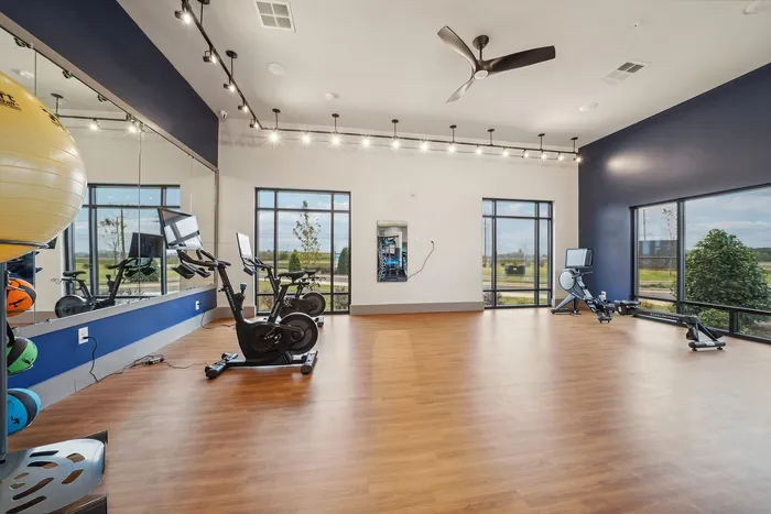 Bright and modern fitness room featuring exercise bikes, treadmills, large mirrors, and expansive windows with scenic views.
