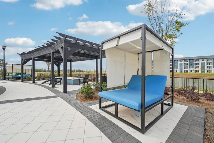 Luxurious outdoor lounge area featuring modern pergolas, stylish blue daybeds, and a scenic backdrop perfect for relaxation.