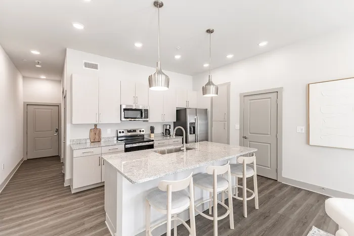 Bright and modern kitchen with sleek granite countertops, stylish pendant lighting, and a spacious island with cozy seating.