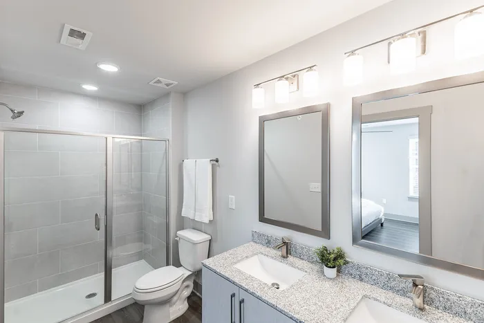 Modern bathroom with sleek glass shower, elegant vanity with dual sinks, and soft, ambient lighting.
