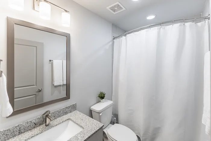 Elegant modern bathroom showcasing a sleek granite countertop, contemporary light fixtures, and a stylish shower curtain.
