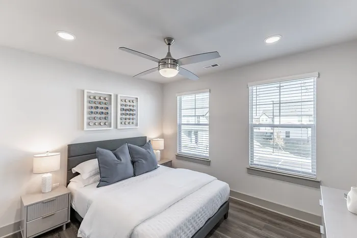 Bright and modern bedroom with stylish decor, featuring a comfortable bed, elegant lighting, and large windows for natural light.