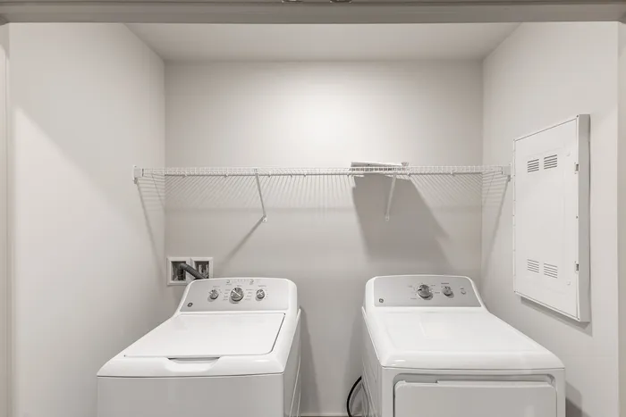 Modern laundry room with sleek washer and dryer under a practical storage shelf, perfect for efficient living.