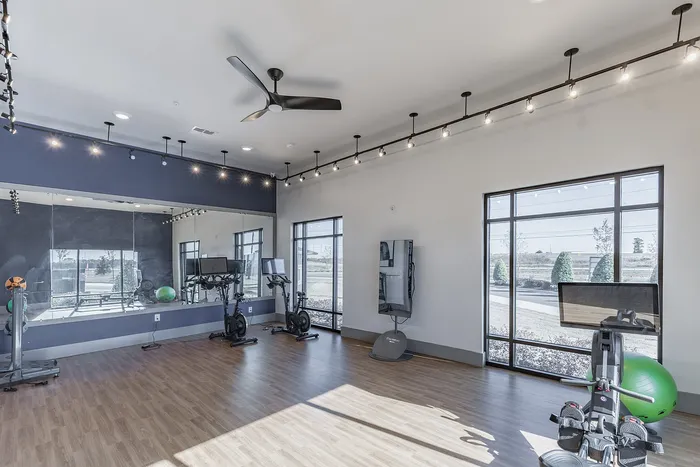 Bright and modern fitness room featuring state-of-the-art exercise equipment and large windows with natural light.