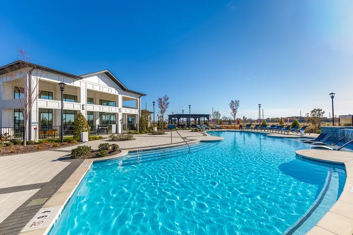 Luxurious apartment complex featuring a sparkling outdoor swimming pool and modern architecture, perfect for relaxation and leisure.