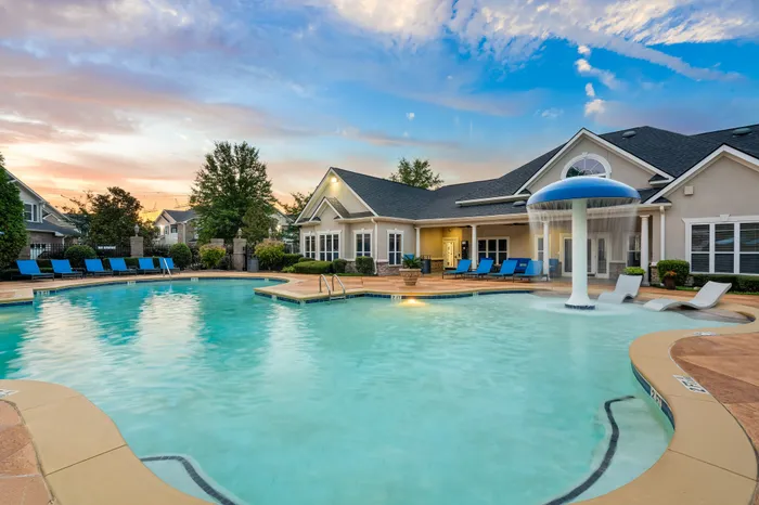 Luxurious apartment complex showcasing a sparkling pool with elegant lounge chairs and scenic sunset views.