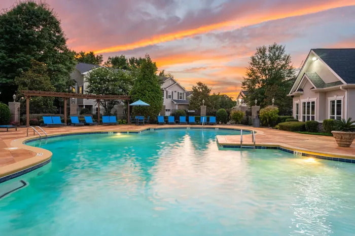 Inviting residential pool area with elegant seating under a stunning sunset sky, ideal for relaxation and leisure.