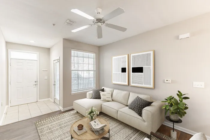 Bright and elegant living room featuring a cozy beige sectional sofa, modern artwork, and a stylish indoor plant.