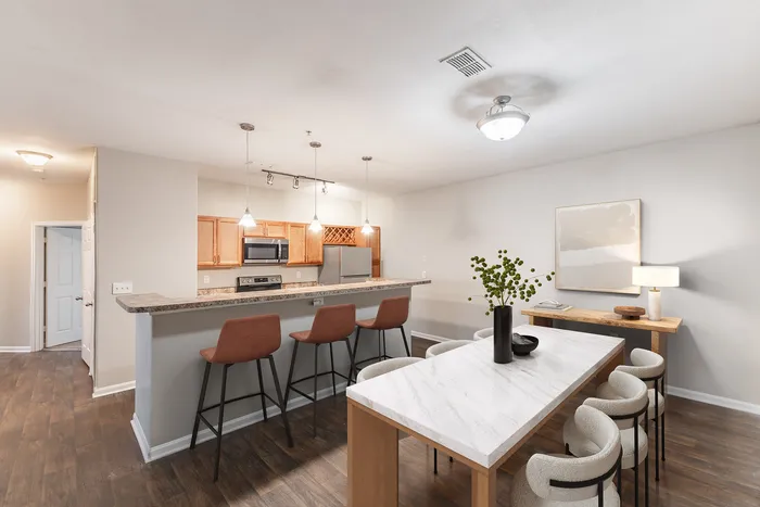 Modern open-concept kitchen and dining area with sleek finishes, elegant bar seating, and warm lighting, offering a stylish and inviting space for entertaining.