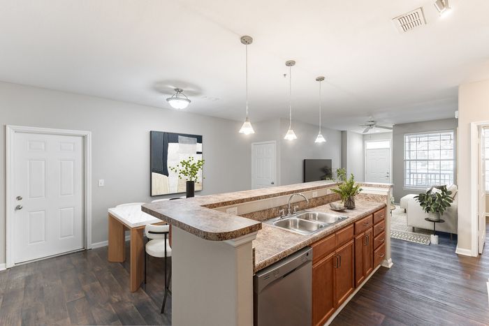 Contemporary open kitchen with elegant pendant lighting, stylish countertops, and a view into a bright living area with natural light.