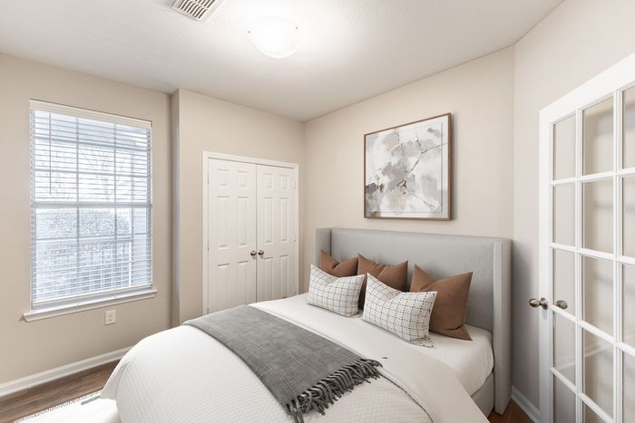 Bright and stylish bedroom featuring a plush bed with decorative pillows, modern art, and ample natural light through large windows.