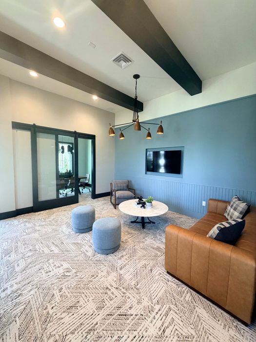 Contemporary living room with a modern chandelier, stylish leather sofa, and elegant decor, complemented by soft lighting and tasteful design.