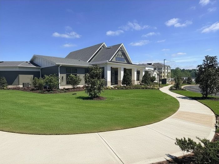 Charming residential complex featuring manicured lawns, modern architecture, and inviting pathways under a bright blue sky.