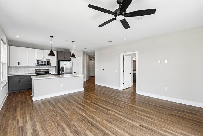 Contemporary open-concept apartment with stylish kitchen, hardwood floors, and modern lighting fixtures.