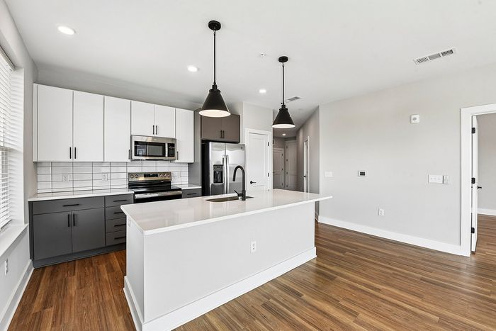 Modern kitchen with sleek white cabinets, stainless steel appliances, and a spacious island with elegant pendant lighting.