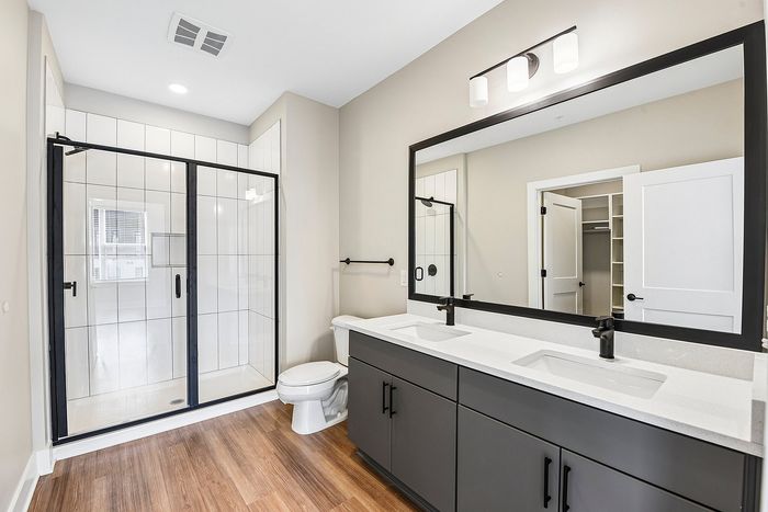 Elegant bathroom with a spacious shower, sleek double vanity, and modern fixtures, enhanced by natural lighting.