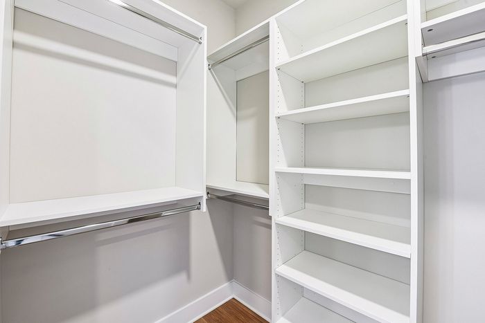Modern walk-in closet with elegant white shelving and ample hanging space, showcasing stylish and efficient storage solutions.