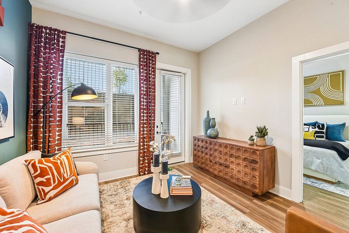 Bright and inviting living room with vibrant decor and a view into a cozy bedroom, featuring stylish furniture and modern touches.