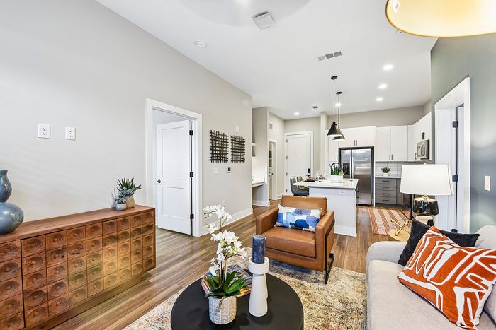 Chic living area with modern furniture, stylish decor, and open-plan kitchen featuring sleek cabinetry and stainless steel appliances.