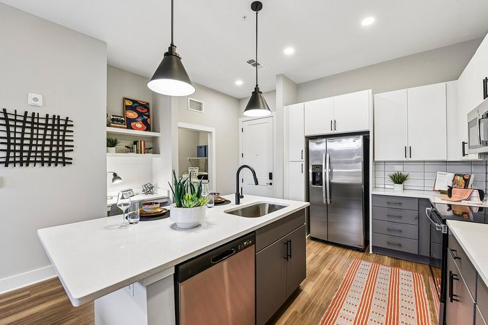 Modern kitchen with sleek cabinetry, stainless steel appliances, and stylish pendant lighting. Features a spacious island with a built-in sink, elegant countertop, and chic decor accents.