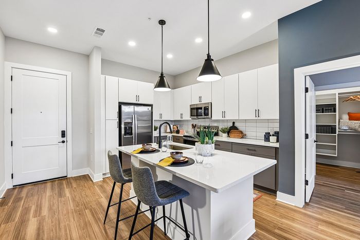 Modern kitchen with sleek white cabinetry, stylish pendant lighting, and a spacious island with seating, perfect for entertaining.