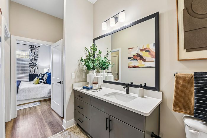 Chic modern bathroom with elegant vanity, contemporary decor, and a glimpse into a cozy, stylish bedroom.