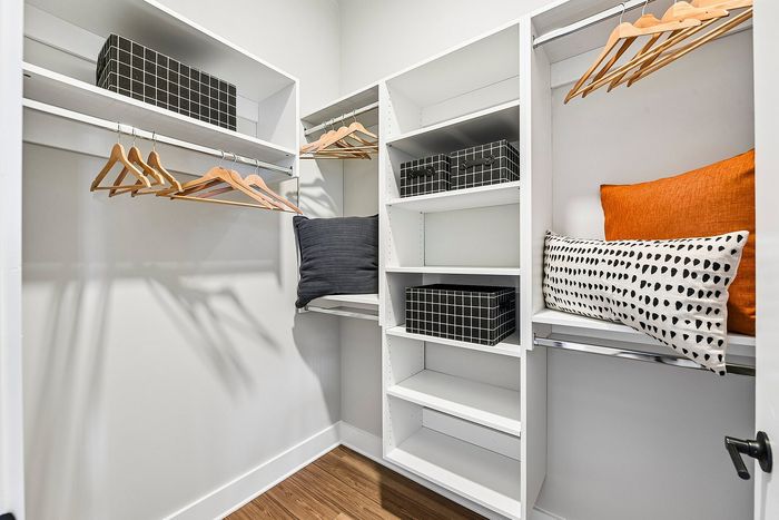 Luxurious walk-in closet with sleek white shelving and modern storage solutions, offering abundant space for organization.