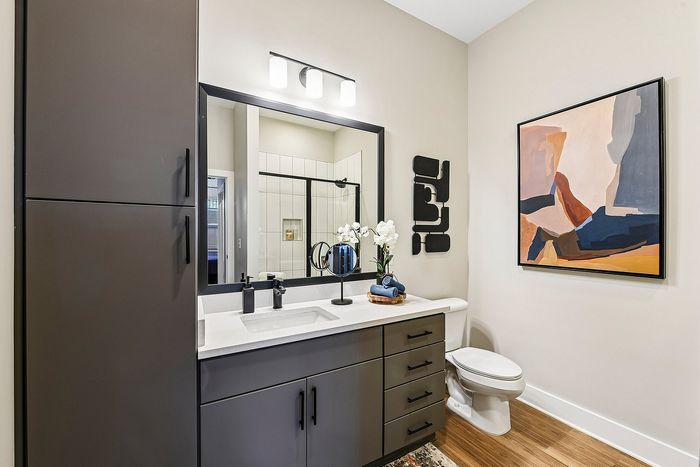 Contemporary bathroom with sleek dark cabinetry, elegant decor, and modern artwork, creating a luxurious and inviting ambiance.