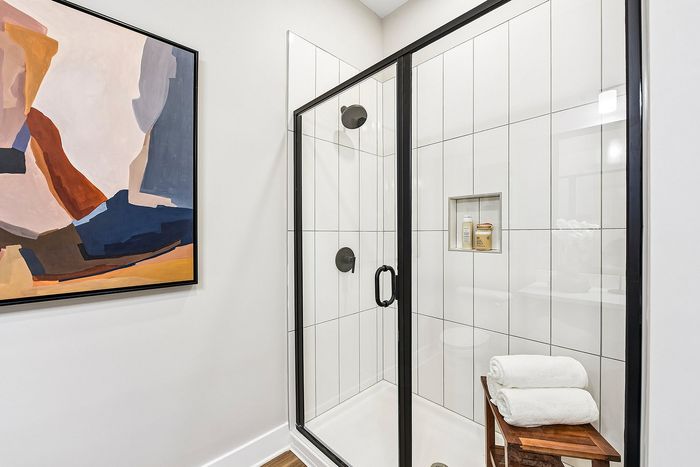 Modern bathroom with sleek glass shower, stylish abstract art, and elegant tile design offering a luxurious experience.