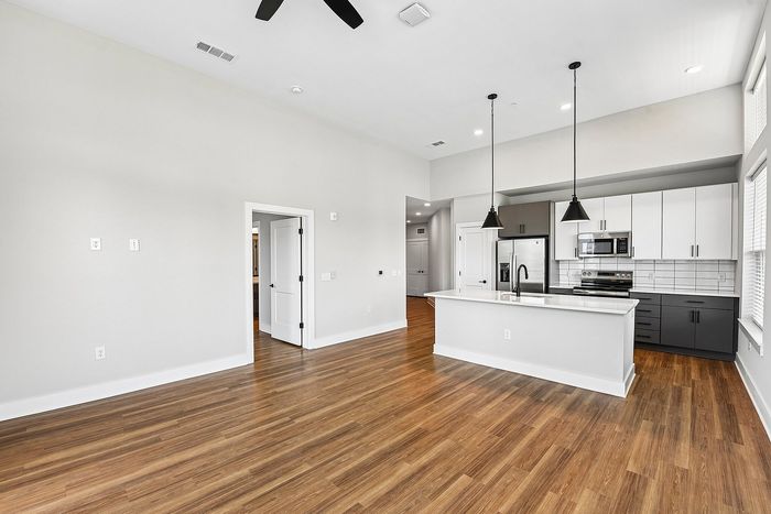Modern open-concept kitchen with sleek countertops, elegant lighting, and spacious hardwood flooring.