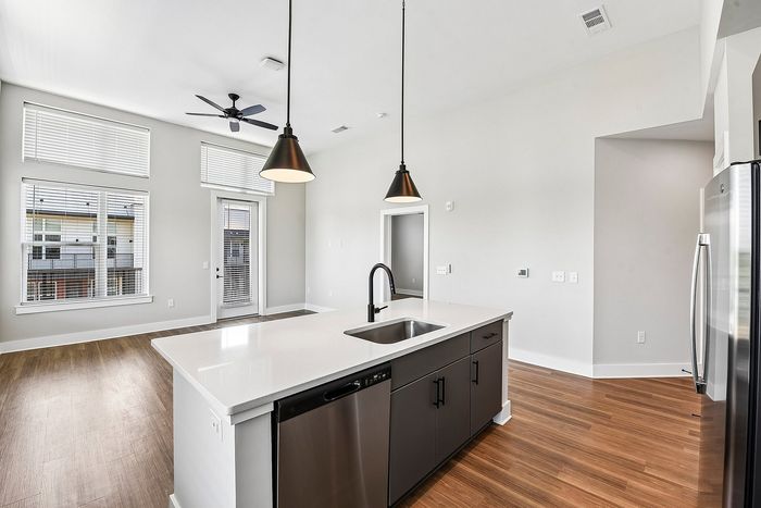 Bright and modern kitchen with sleek countertops, pendant lighting, and open living space.