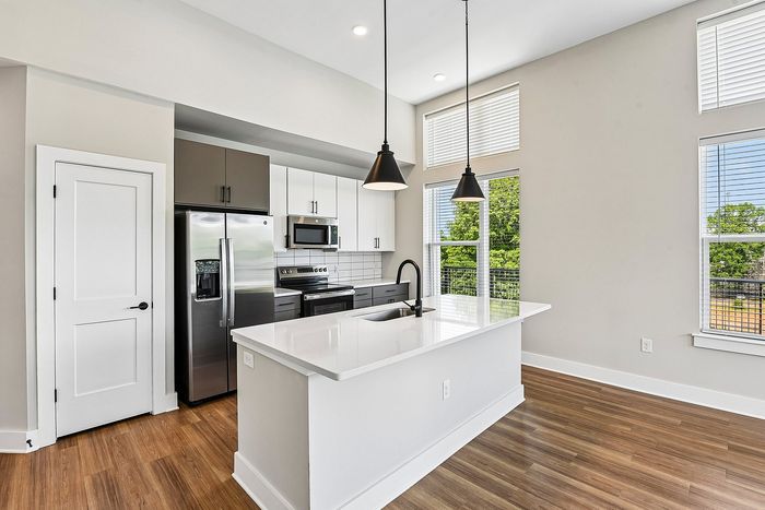 Sleek modern kitchen with a spacious island, stainless steel appliances, and bright natural lighting.