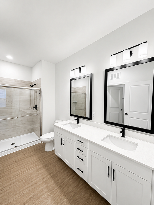 Modern bathroom with dual sinks, sleek black fixtures, and a spacious glass-enclosed shower.