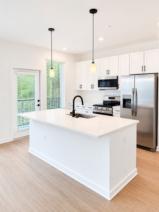 Modern kitchen with sleek white cabinetry, stainless steel appliances, and elegant pendant lighting over a spacious island.