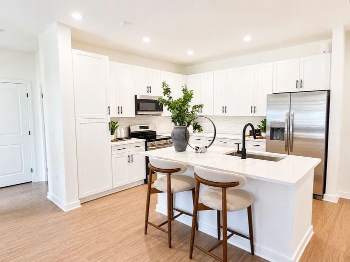Bright, modern kitchen with sleek white cabinetry, stainless steel appliances, and a spacious island with seating.