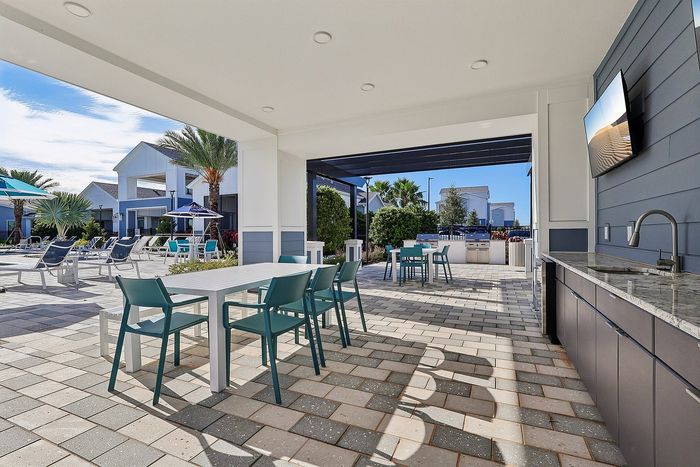 Luxurious outdoor lounge area with modern dining setup, overlooking a pristine pool and vibrant palm trees, perfect for relaxation and entertainment.