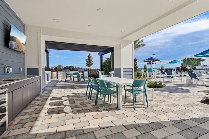 Inviting outdoor lounge area with modern patio furniture, shaded seating, and a sparkling pool under clear skies.