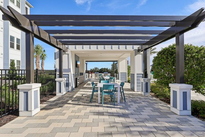 Chic outdoor patio with sleek pergola, modern dining area, and lush greenery, perfect for entertaining.