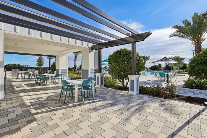 Beautiful outdoor patio area with modern pergola, stylish seating, and a refreshing poolside view surrounded by lush greenery.