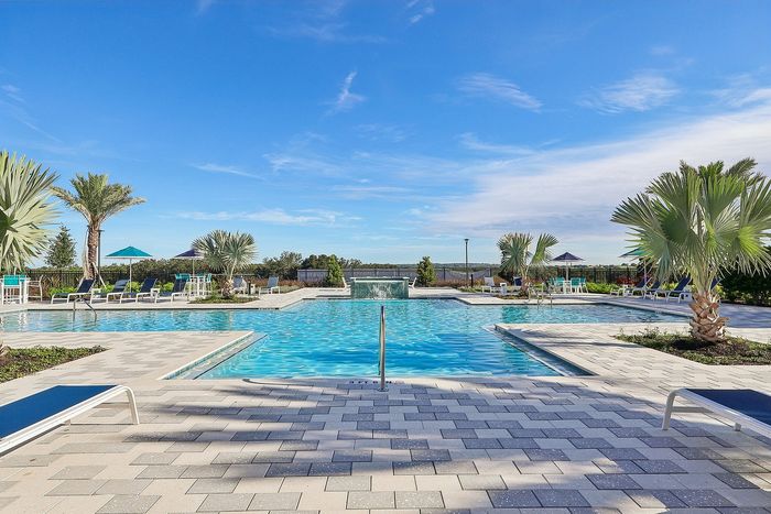 Luxurious resort-style pool with sparkling blue water, surrounded by palm trees and sun loungers, perfect for a relaxing getaway.