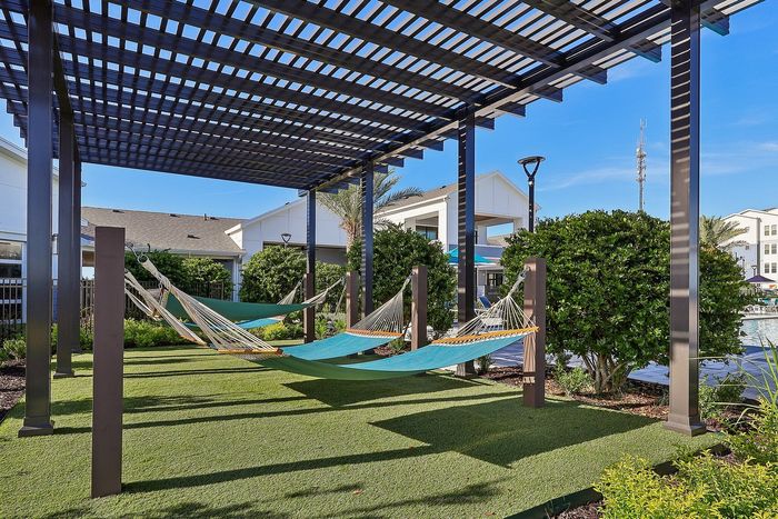 Tranquil outdoor space with cozy hammocks under a modern pergola, perfect for relaxation near a pristine pool.