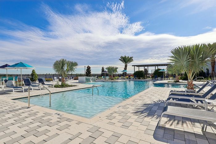 Luxurious poolside oasis with sun loungers, vibrant palm trees, and crystal-clear water under a bright blue sky.