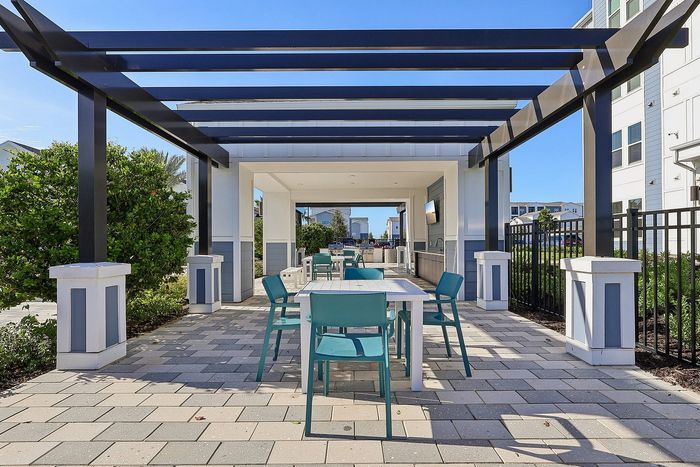 Chic outdoor seating area with modern pergola, perfect for relaxation and gatherings, set against a sunny blue sky.