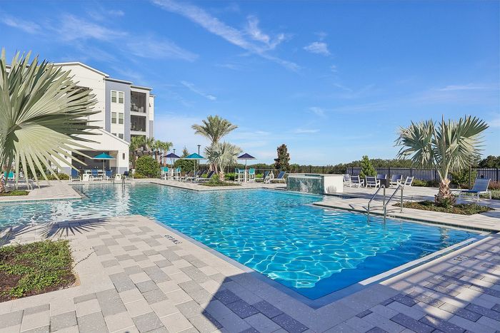 Luxurious resort-style swimming pool with lounge chairs and lush tropical landscaping, perfect for relaxation and leisure.