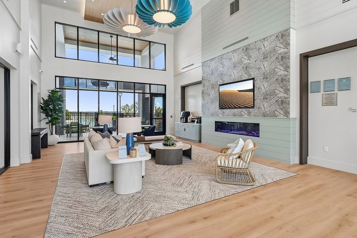 Bright and modern living space with high ceilings, elegant lighting fixtures, and large windows offering a stunning view. Features a cozy seating area, sleek fireplace, and stylish decor.