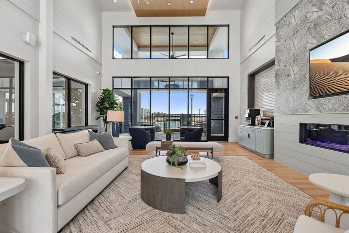 Bright and airy living room featuring high ceilings, contemporary decor, and expansive windows offering beautiful outdoor views.