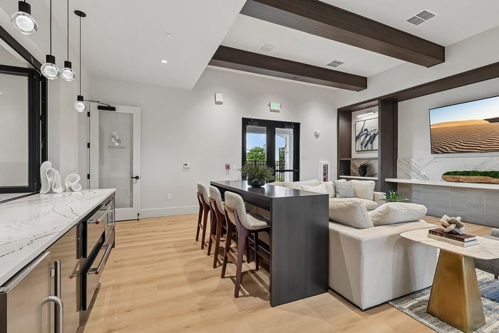 Elegant living space with contemporary design, featuring a marble countertop kitchen, stylish dining area, and cozy lounge with a large flat-screen TV.