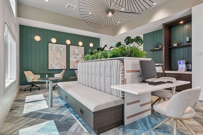 Modern communal workspace featuring sleek furniture, lush greenery, and stylish wall art, creating an inviting and productive environment.